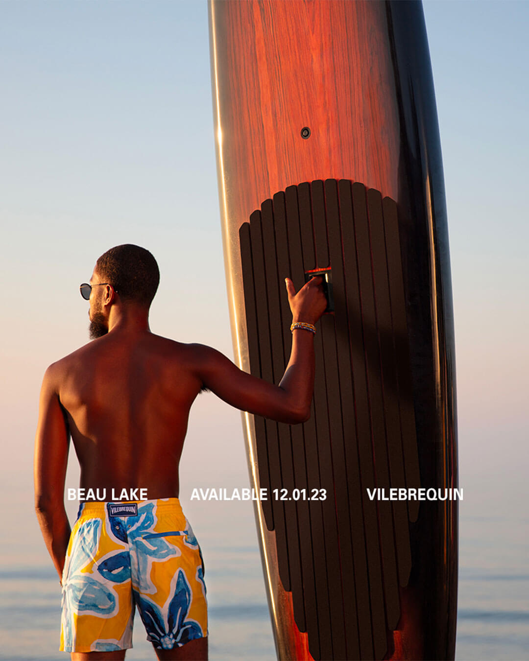 Man standing next to a surfboard.